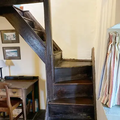 an old wooden staircase in a room with a desk at Llynhillyn Cottage in Presteigne