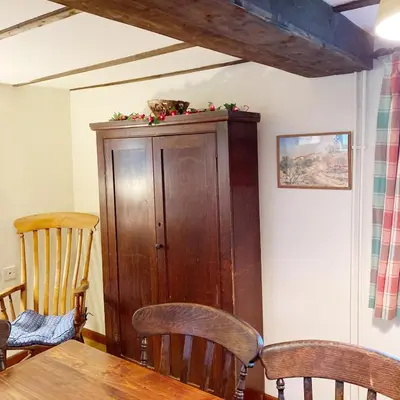a wooden cabinet in a room with a table and chairs at Llynhillyn Cottage in Presteigne