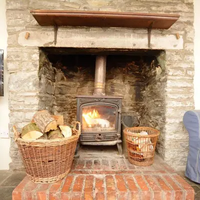 a stone fireplace with two baskets in front of it at Llynhillyn Cottage in Presteigne