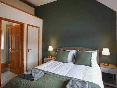 a bedroom with a bed with green walls and two lamps at Uk46557 - Caradoc in Church Stretton