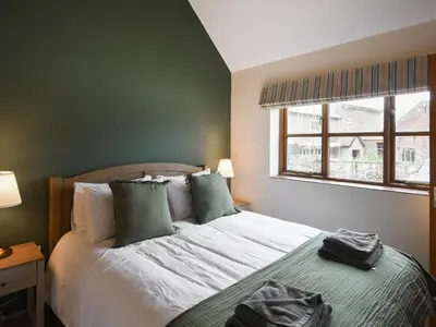 a bedroom with a bed with green walls and a window at Uk46557 - Caradoc in Church Stretton
