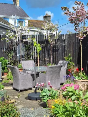 a patio with a table and chairs and flowers at Brynarfor near Aberaeron in Llanon