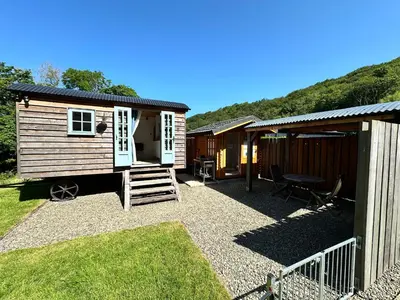 a small cabin with a patio and a house at Cwt Bugail Aeron in Aberaeron