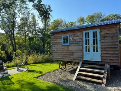 a small wooden cabin with a door and a porch at Cwt Bugail Aeron in Aberaeron
