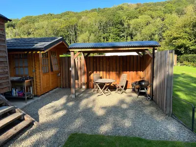 a patio with a table and chairs next to a cabin at Cwt Bugail Aeron in Aberaeron