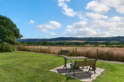 two park benches and a picnic table in a field at Granary Cottage a Shropshire haven in Church Stretton