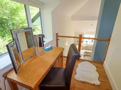 a desk with a mirror and a chair in a room at Bryn Golau in Llangollen