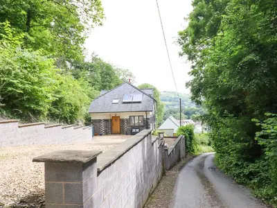 a house behind a brick wall and a road at Bryn Golau in Llangollen
