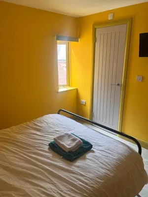 a yellow room with a bed with a towel on it at Tumbledown Hotel in Shrewsbury