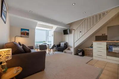 a living room with a couch and a staircase at Modern Sea View Apartment in Aberdyfi