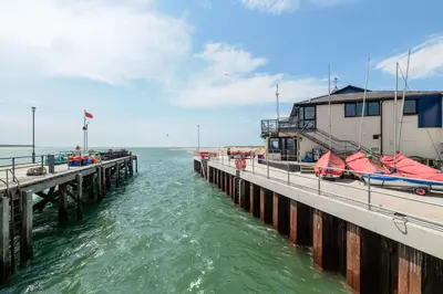a pier with boats on the water next to a building at Modern Sea View Apartment in Aberdyfi