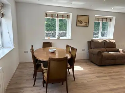 a dining room with a table and chairs and a couch at Kimberly House in Arthog