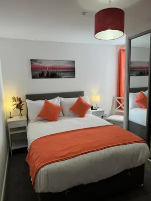 a bedroom with a large bed with orange pillows at The Bear Apartments in Llandovery