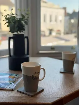 two coffee cups sitting on a wooden table at The Nook Castle Street Ludlow in Ludlow