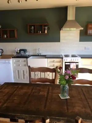 a kitchen with a wooden table with a vase of flowers at A Tranquil Retreat for Two in Pont-Robert
