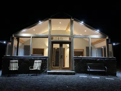 a building with two chairs in front of it at night at Red Kite Cottage in Llangunllo