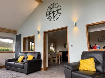 a living room with two leather chairs and a clock on the wall at Oak View Cottage in Llangunllo