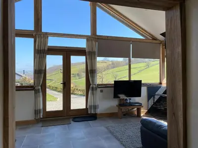 a living room with a large window and a television at Oak View Cottage in Llangunllo