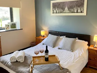 a bedroom with a bed with two glasses of wine at Oak View Cottage in Llangunllo