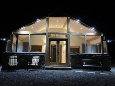 a building with two chairs in front of it at night at Oak View Cottage in Llangunllo