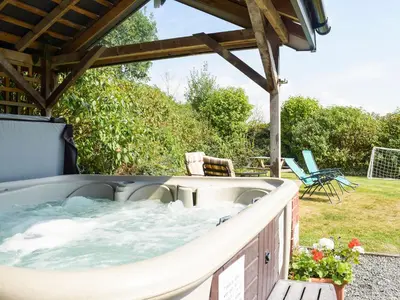 a jacuzzi tub on the patio of a house at Heyope Cottage in Llangunllo