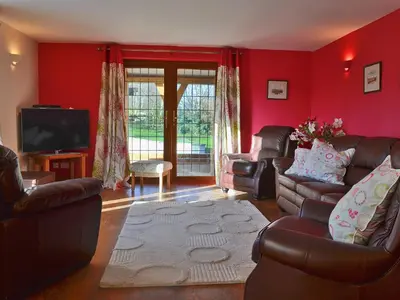 a living room with red walls and leather furniture at Celyn in Montgomery