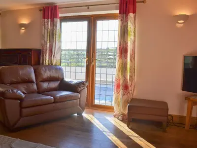 a living room with a leather couch and a large window at Celyn in Montgomery