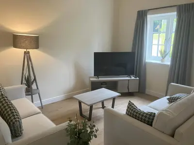 a living room with two white couches and a tv at Tedsmore Cottages in Oswestry