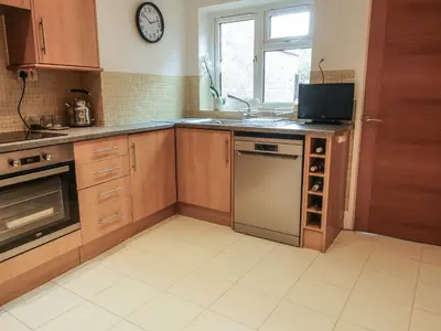 a kitchen with wooden cabinets and a sink and a dishwasher at Riverbank in Shrewsbury