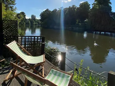 two chairs sitting next to a lake with a swan at Riverbank in Shrewsbury