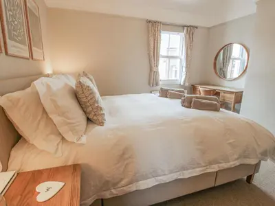 a bedroom with a large white bed and a table at Riverbank in Shrewsbury