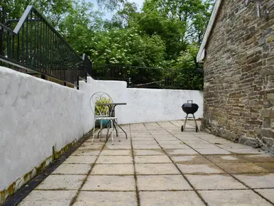 a patio with a table and chairs next to a wall at The Dairy - Uk47471 in Llanerch-Aeron
