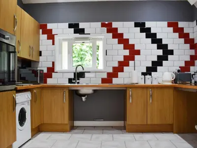 a kitchen with a sink and a red and white tile wall at The Dairy - Uk47471 in Llanerch-Aeron