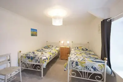 a bedroom with two beds and a table and a window at Drws Y Coed in Tal-gareg