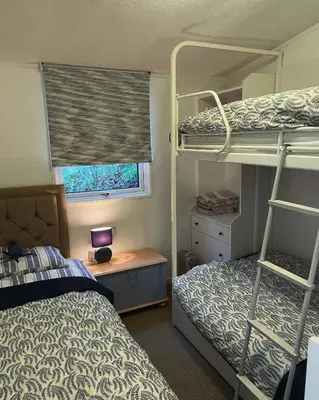 a bedroom with two bunk beds and a desk and a window at Cosy private Chalet in Tywyn