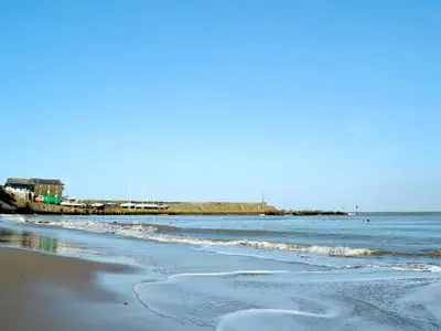 a beach with the ocean and a pier in the background at The Granary - Or3 in Henfynyw Upper