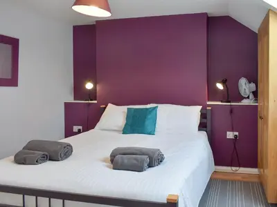 a bedroom with a large bed with purple walls at The Coach House - Or4 in Henfynyw Upper