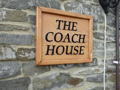 a sign that reads the coach house on a stone wall at The Coach House - Or4 in Henfynyw Upper