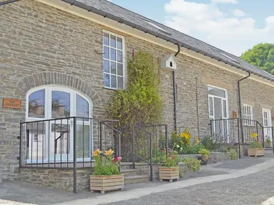 a brick building with a gate and some flowers at The Coach House - Or4 in Henfynyw Upper