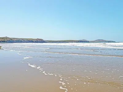 a beach with waves coming in from the ocean at The Cow Shed - Or5 in Henfynyw Upper