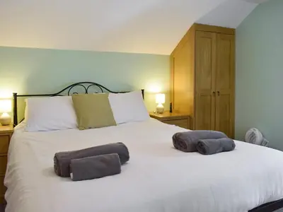 a bedroom with a large white bed with two towels on it at The Cow Shed - Or5 in Henfynyw Upper