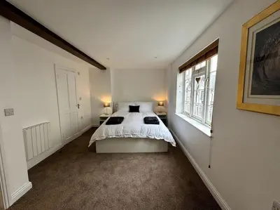 a white bedroom with a bed and a window at Penny Black Apartment, Kington in Kington