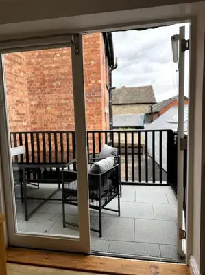 an open door to a balcony with a table and chairs at Penny Black Apartment, Kington in Kington