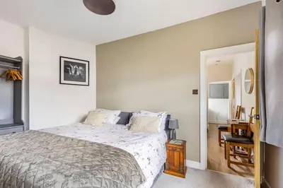 a white bedroom with a bed and a mirror at Castell Bach in Llangollen