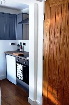 a kitchen with a stove and a wooden cabinet at Castell Bach in Llangollen