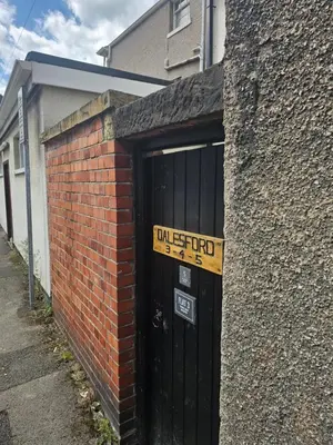 a brick building with a black door with a sign on it at Castell Bach in Llangollen