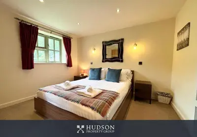 a bedroom with a bed with blue pillows and a mirror at Beautiful Cottage in the Heart of Shrewsbury in Shrewsbury