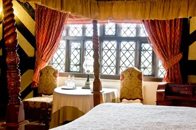 a bedroom with a bed and a table and windows at Albright Hussey Manor in Shrewsbury