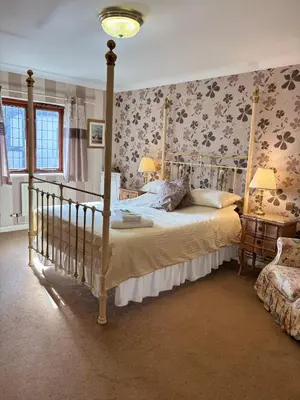 a bedroom with a canopy bed and floral wallpaper at Albright Hussey Manor in Shrewsbury