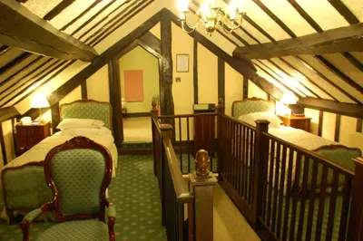 a bedroom with two beds and chairs in a attic at Albright Hussey Manor in Shrewsbury